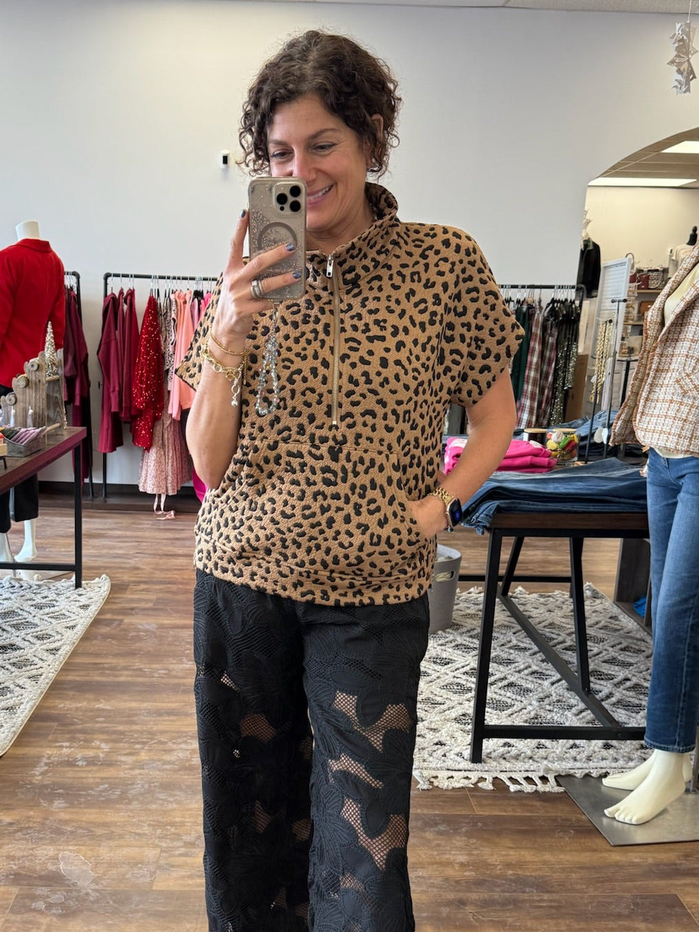 Person wearing a leopard print top and black pants in a store setting.