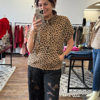 Person wearing a leopard print top and black pants in a store setting.